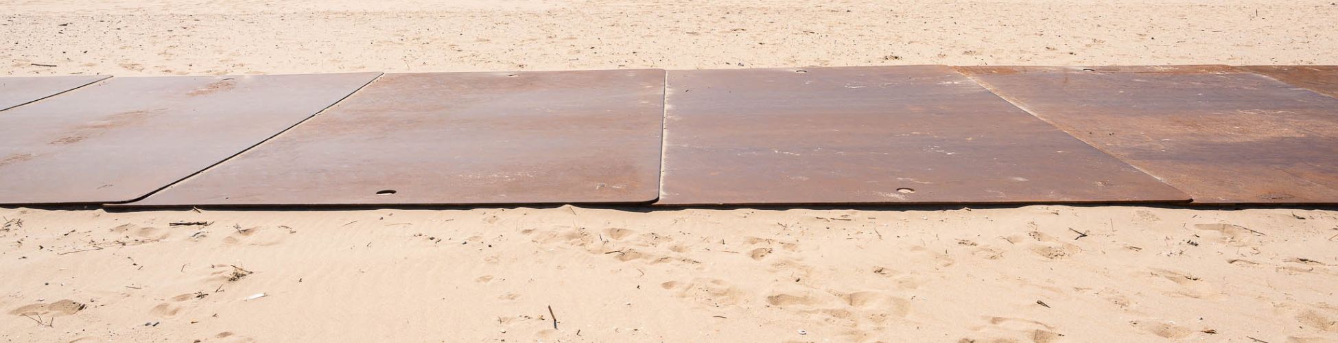 Tijdelijke wegverharding met stalen rijplaten op het strand